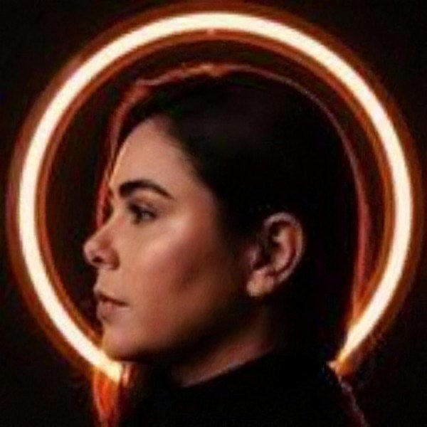 Amanda Pedrosa, de perfil, diante de um anel de luz